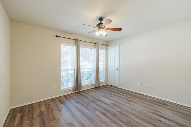 spare room featuring a ceiling fan, baseboards, and wood finished floors