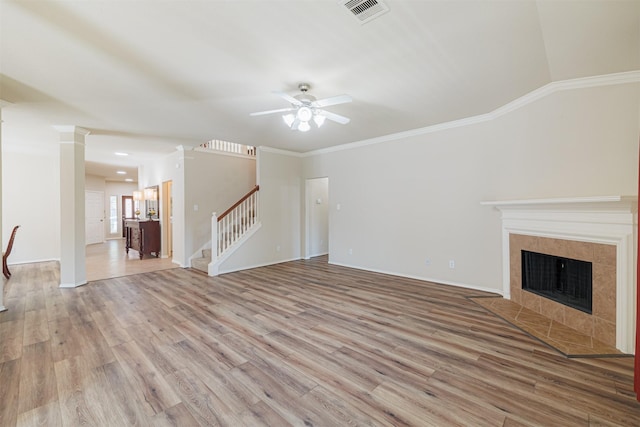 unfurnished living room featuring visible vents, a tiled fireplace, light wood-style flooring, stairs, and crown molding