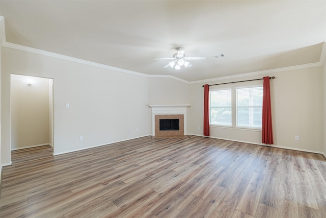 unfurnished living room featuring crown molding, visible vents, a tiled fireplace, ceiling fan, and light wood-type flooring