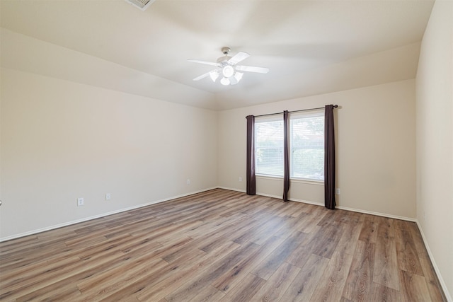 empty room with light wood finished floors, ceiling fan, baseboards, and vaulted ceiling