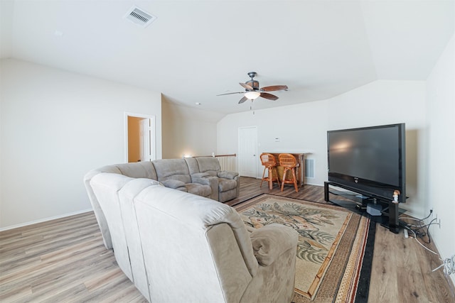 living area featuring ceiling fan, wood finished floors, visible vents, baseboards, and vaulted ceiling