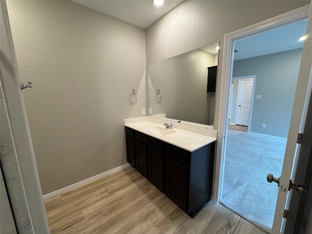 bathroom with baseboards, wood finished floors, and vanity