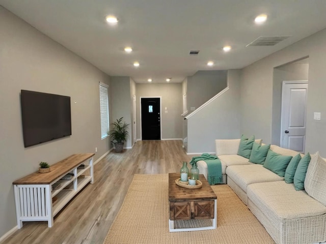 living room with light wood-style flooring, visible vents, and recessed lighting