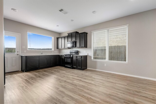 23947 Falling Daylight Dr, Hockley, TX 77447 - kitchen with black appliances, light wood finished floors, baseboards, light countertops, and dark cabinetry