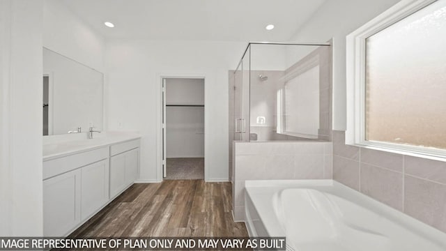 bathroom with a stall shower, wood finished floors, a spacious closet, vanity, and a bath