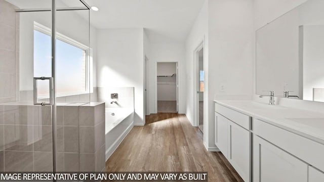 full bath with wood finished floors, a walk in closet, vanity, a shower stall, and a bath