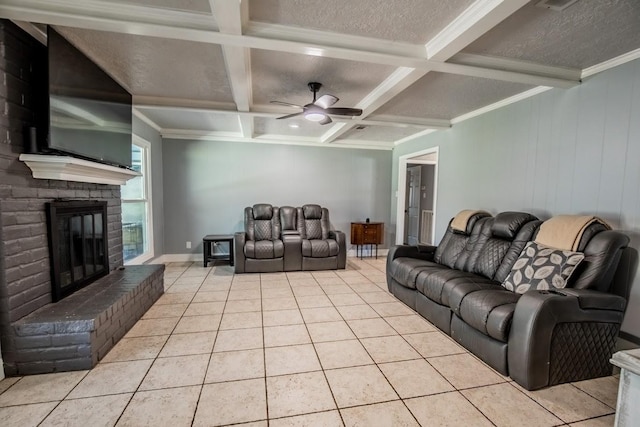 living area with light tile patterned flooring, coffered ceiling, beam ceiling, a glass covered fireplace, and ceiling fan