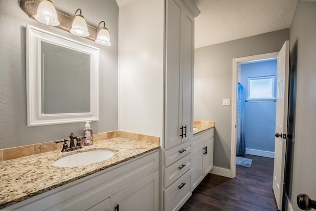 bathroom featuring wood finished floors, vanity, and baseboards