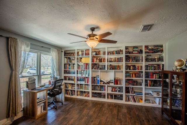 office featuring bookshelves, a textured ceiling, wood finished floors, and ceiling fan