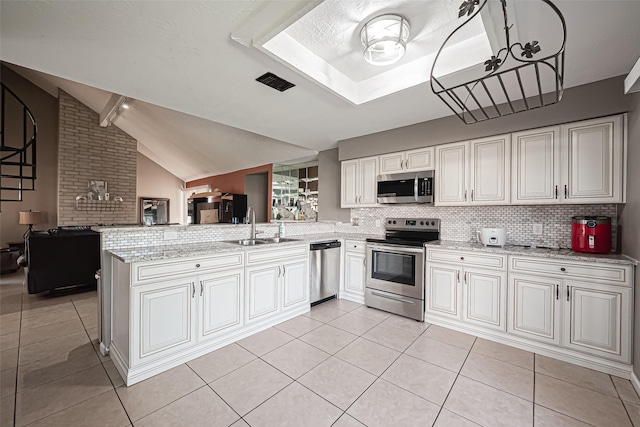 kitchen with appliances with stainless steel finishes, open floor plan, light tile patterned flooring, a sink, and a peninsula