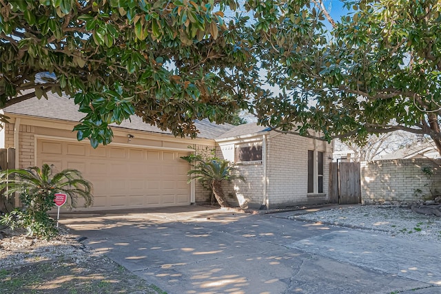 view of front of property with a garage, brick siding, fence, driveway, and roof with shingles