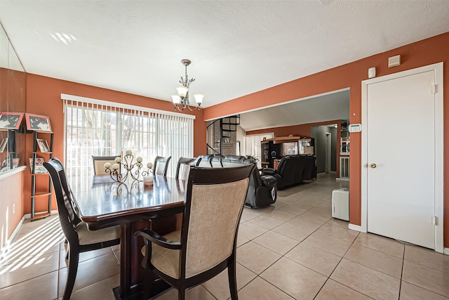 dining area featuring a chandelier, light tile patterned floors, a textured ceiling, and stairs