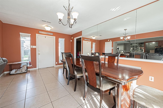 dining space featuring baseboards, light tile patterned flooring, visible vents, and a notable chandelier