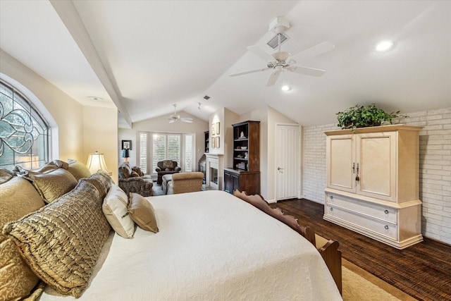 bedroom featuring brick wall, a fireplace, a ceiling fan, vaulted ceiling, and dark wood finished floors