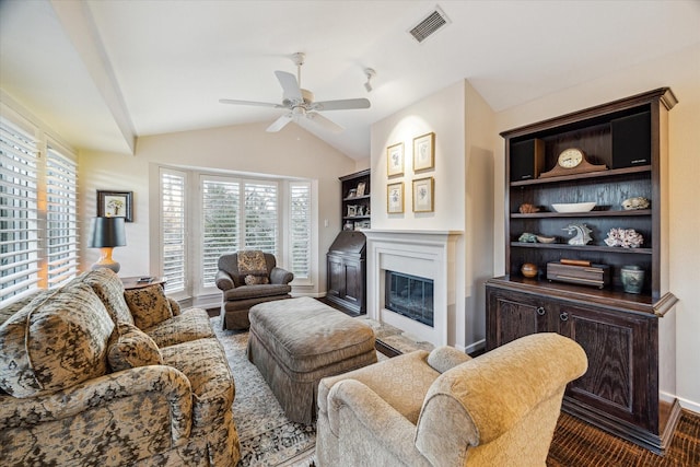 living room with baseboards, visible vents, a ceiling fan, a glass covered fireplace, and lofted ceiling