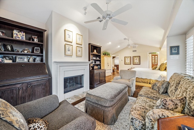 living room featuring lofted ceiling, a fireplace with flush hearth, ceiling fan, and wood finished floors