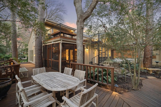 wooden deck with outdoor dining space, a sunroom, and stairs