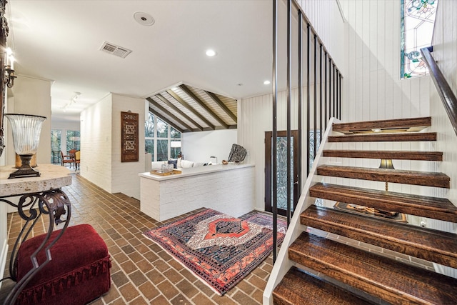 staircase with vaulted ceiling, brick floor, visible vents, and recessed lighting