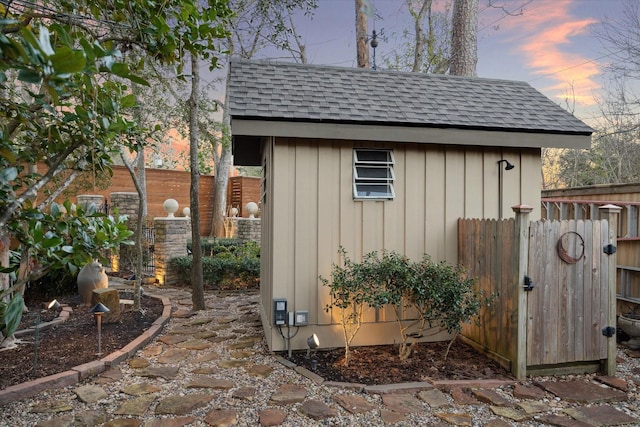 outdoor structure at dusk with an outdoor structure, a shed, and fence