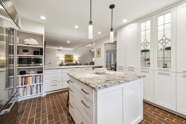 kitchen featuring open floor plan, a center island, brick floor, white cabinetry, and recessed lighting