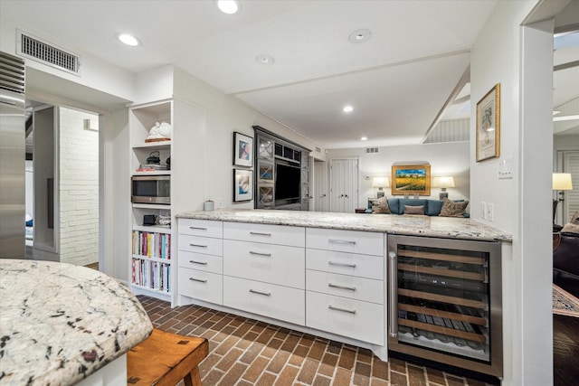 interior space featuring visible vents, wine cooler, stainless steel microwave, brick floor, and recessed lighting