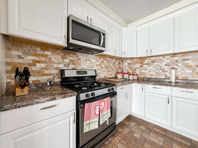 kitchen featuring dark stone counters, stainless steel appliances, tasteful backsplash, and white cabinetry