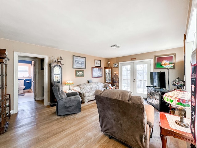 living area featuring light wood-style floors, visible vents, a wealth of natural light, and french doors