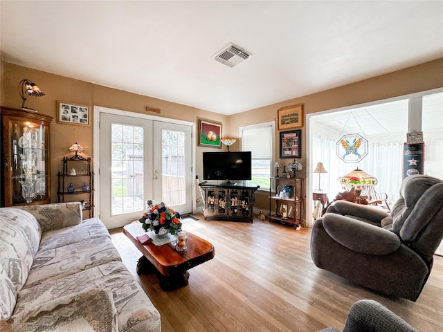 living area featuring light wood-type flooring, french doors, and visible vents