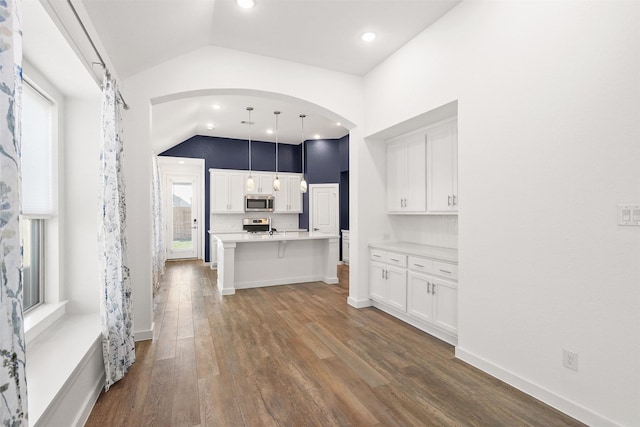 kitchen featuring dark wood-style floors, lofted ceiling, light countertops, appliances with stainless steel finishes, and white cabinets