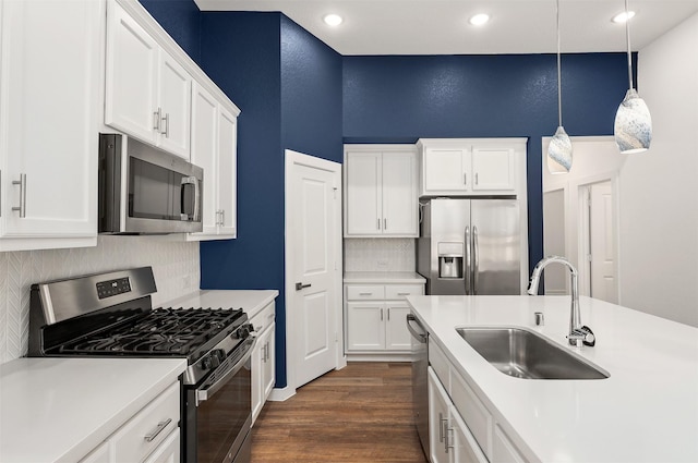 kitchen with stainless steel appliances, a sink, white cabinetry, light countertops, and tasteful backsplash