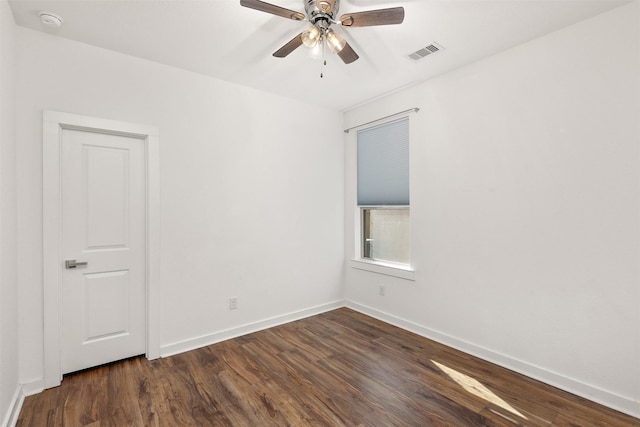 unfurnished room featuring a ceiling fan, visible vents, dark wood finished floors, and baseboards