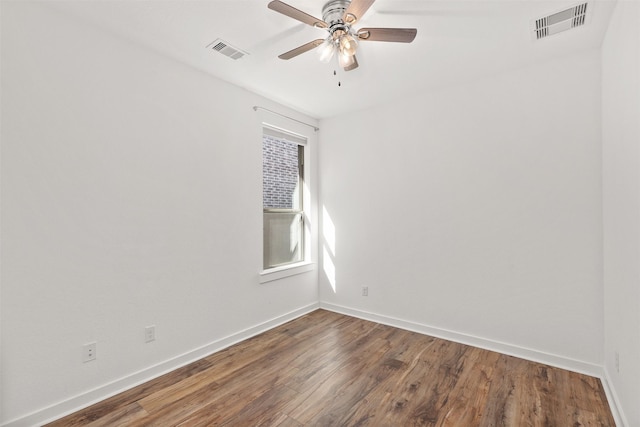 empty room with a ceiling fan, visible vents, baseboards, and wood finished floors