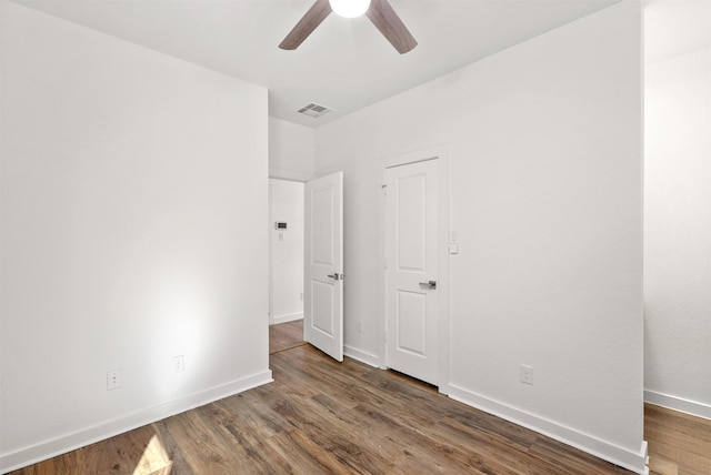 unfurnished bedroom with a ceiling fan, visible vents, baseboards, and wood finished floors