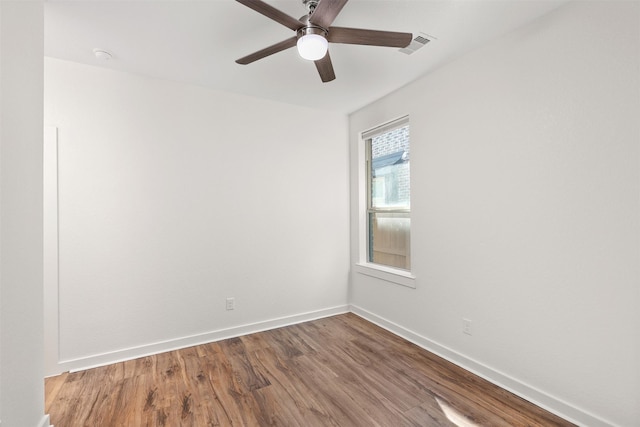 spare room featuring ceiling fan, wood finished floors, visible vents, and baseboards