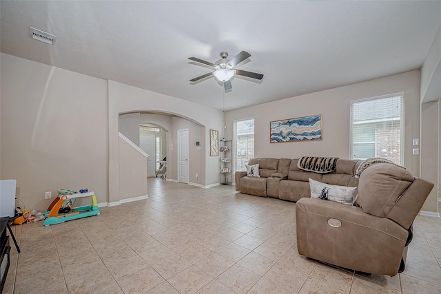 living area featuring a ceiling fan, arched walkways, visible vents, and light tile patterned flooring