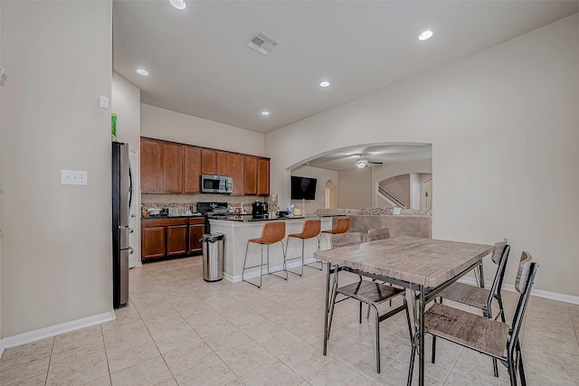 kitchen with arched walkways, a peninsula, visible vents, appliances with stainless steel finishes, and brown cabinetry