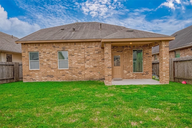 rear view of house with a yard, brick siding, a patio, and a fenced backyard