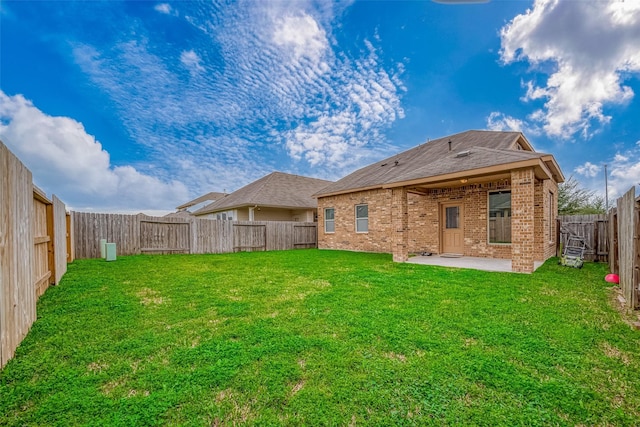 back of house featuring a fenced backyard, a patio, a lawn, and brick siding