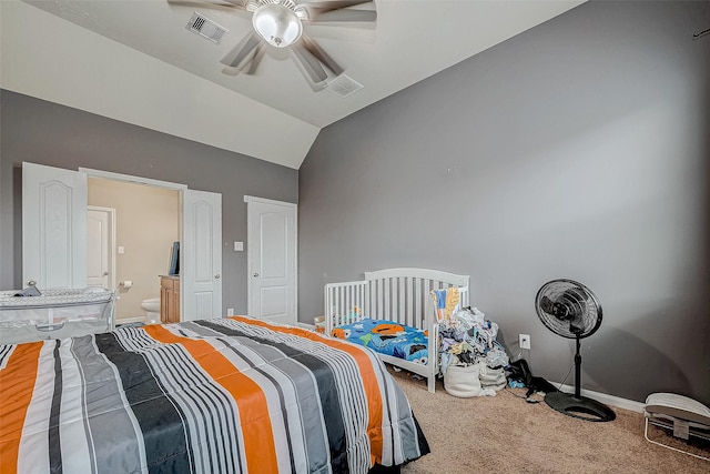 bedroom featuring carpet flooring, visible vents, baseboards, vaulted ceiling, and ensuite bath