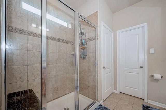 bathroom featuring a stall shower, tile patterned flooring, and baseboards