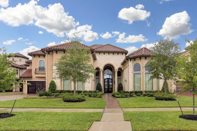 mediterranean / spanish-style home featuring a tile roof, a front lawn, french doors, and stucco siding