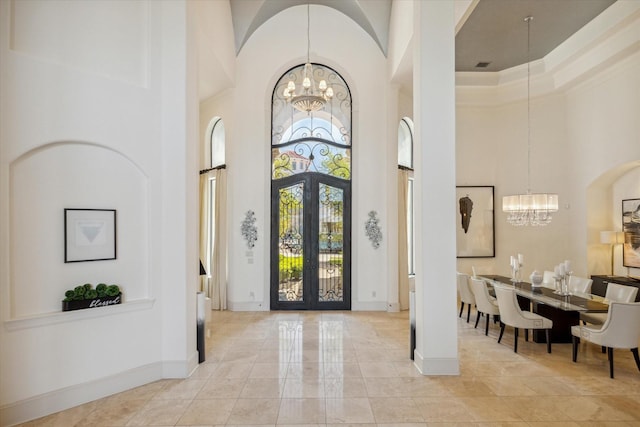 foyer entrance featuring baseboards, visible vents, a high ceiling, french doors, and a chandelier