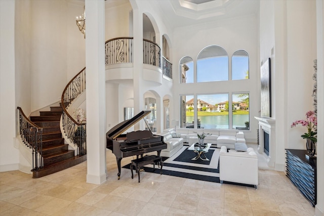 living area with a fireplace, a towering ceiling, a chandelier, baseboards, and stairs