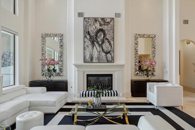 living room with visible vents, a glass covered fireplace, and a towering ceiling