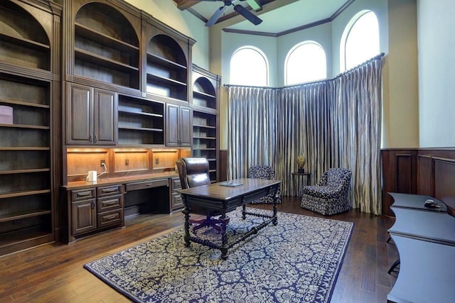 home office featuring dark wood-style floors, a ceiling fan, built in desk, and wainscoting