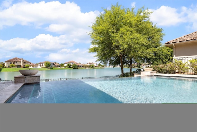 view of swimming pool featuring a water view, an infinity pool, and a patio