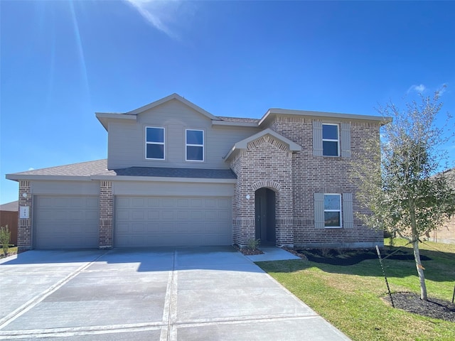 traditional home featuring an attached garage, driveway, brick siding, and a front yard