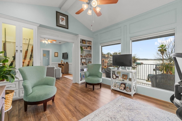 sitting room with a ceiling fan, french doors, lofted ceiling with beams, and wood finished floors