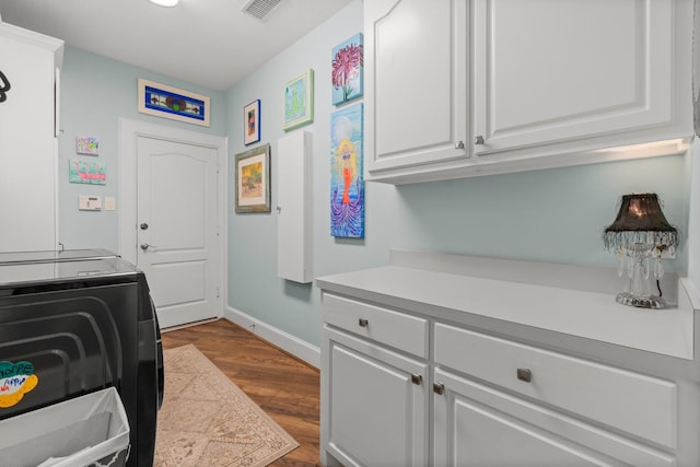 clothes washing area featuring dark wood-style floors, cabinet space, visible vents, and baseboards