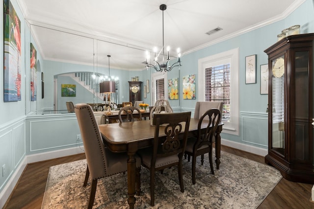 dining room featuring a decorative wall, a notable chandelier, dark wood-style flooring, visible vents, and ornamental molding